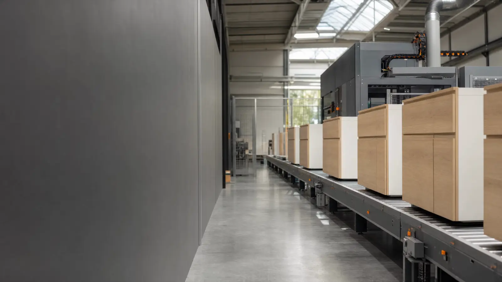 Rij eiken keukenkasten op een rollenbaan in een lichte keukenfabriek
